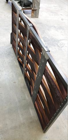 a wooden bench sitting on top of a cement floor next to a metal rail with wood slats