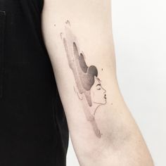 a woman's arm with a watercolor painting style tattoo on the left upper arm