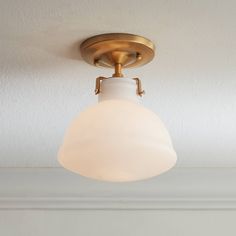 a light fixture with a white glass shade hanging from it's center point on the ceiling