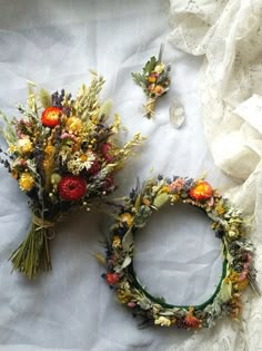 two wreaths with flowers are laying on a white sheet