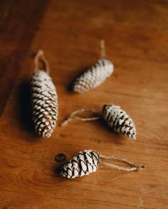 three pine cones on a wooden table with twine and string hanging from the top