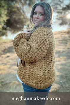 a woman wearing a yellow sweater and jeans standing in the grass with her hands on her hips