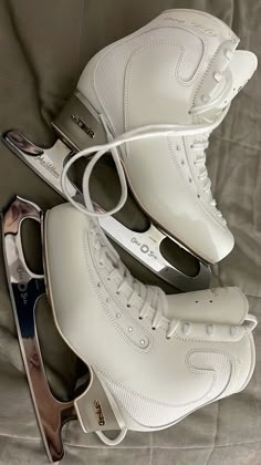 three pairs of white shoes sitting on top of a bed next to each other,