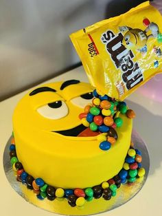 a birthday cake decorated to look like a smiley face holding a bag of m & m's