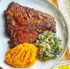 a white plate topped with meat and veggies on top of a wooden table