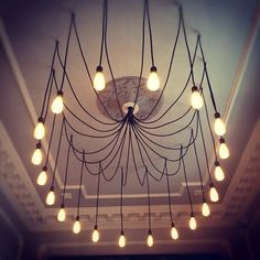 a chandelier with many bulbs hanging from it's ceiling in a room