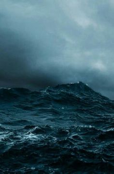 a boat in the middle of an ocean with dark clouds above it and water below