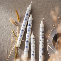 three candles sitting on top of a table next to some dried plants and a plate