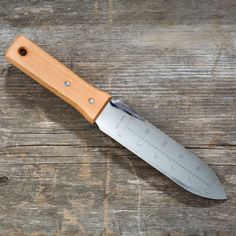 a large knife with a wooden handle on top of a wood table next to a ruler