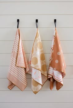 three orange and white towels hanging on the side of a wall next to each other