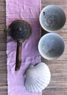 three seashells and two spoons sitting on a purple towel next to each other