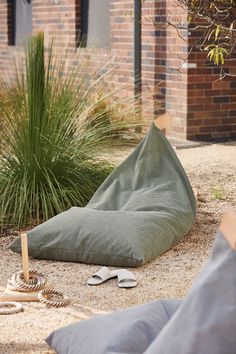 a green bean bag sitting on top of a pile of sand next to a plant