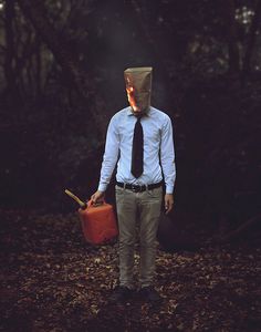 a man with a paper bag on his head holding a fire extinguisher