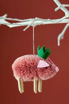 an ornament hanging from a tree branch decorated with pink and green yarns