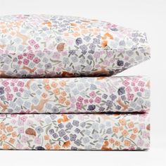 three pillows stacked on top of each other with flowers and leaves printed on the covers