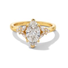 a yellow gold engagement ring with an oval cut diamond and three pear shaped diamonds on the band