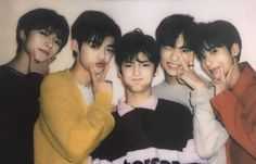 four young men standing next to each other in front of a white wall with their hands on their chins