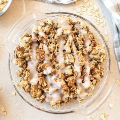 an oatmeal dessert in a glass bowl with icing on top, next to two bowls of oats