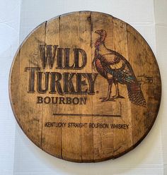 a wooden barrel sign with a turkey on it's side and the words wild turkey bourbon