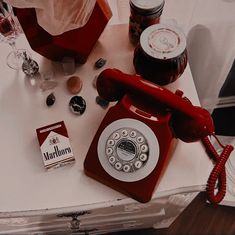 an old fashioned red phone sitting on top of a table next to some condiments