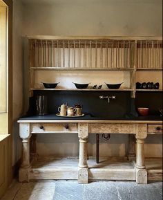 an old fashioned kitchen with black counter tops and wooden shelves on either side of the stove