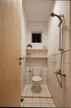 a white toilet sitting inside of a bathroom next to a shower head mounted on a wall