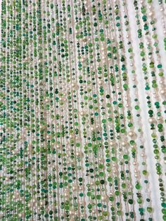 green and white beads are hanging from the ceiling in front of a curtain that is made out of glass beads