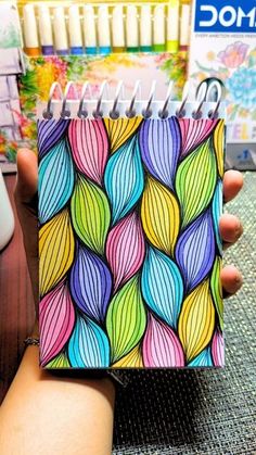 a hand holding a notebook with colorful leaves on it