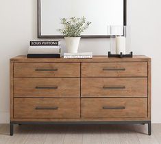 a wooden dresser with a mirror and vase on top