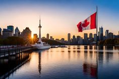 a canadian flag flying in front of a cityscape at sunset with the sun setting