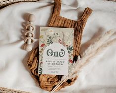 a birthday card sitting on top of a bed next to a feather and wooden bead