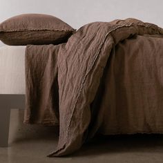 a bed with two pillows on top of it and a blanket over the headboard