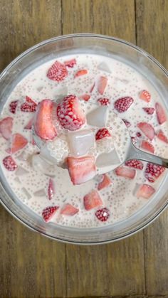 a bowl filled with yogurt and strawberries on top of a wooden table