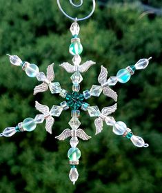 a snowflake ornament hanging from a metal pole with green and white beads