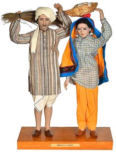 two figurines, one holding a basket and the other standing on a wooden base