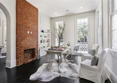 a living room filled with furniture and a fire place next to a brick wall covered in windows