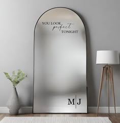 a large mirror sitting on top of a wooden floor next to a vase with flowers