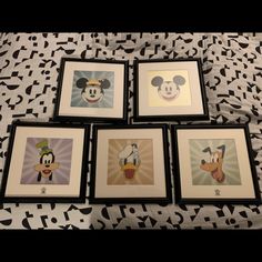 four framed mickey mouse pictures on a black and white bed sheet with an abstract background