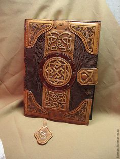 a brown leather book with an intricate design on the front and sides, sitting on a tan background