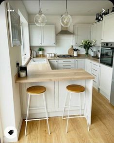 two stools are sitting at the counter in this white and wood themed kitchen area