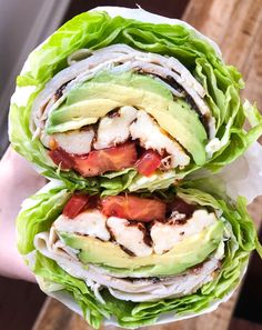 two sandwiches with lettuce, tomatoes and avocado on them are stacked high