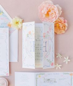 the wedding stationery is laid out with flowers