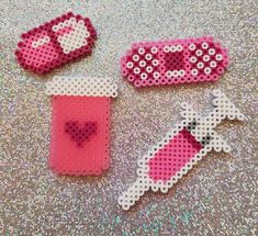 three pieces of pink and white beaded crafting on a silver surface with sequins