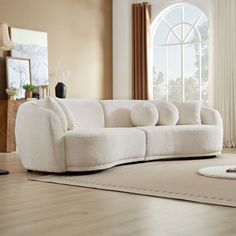 a living room with a white couch, rug and large window in the center area