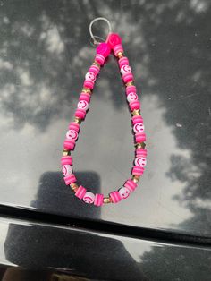 a pink and white beaded necklace on top of a car