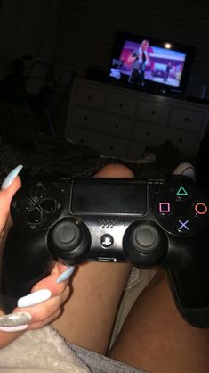 a person holding a video game controller in their hand with a tv in the background