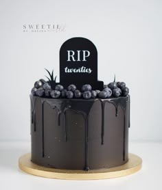 a black cake with blueberries on top and a tombstone sign in the middle that says rip