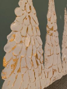 three white and gold christmas trees sitting on top of a table