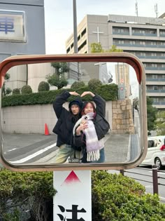 two people standing in front of a mirror with their hands up to the camera and one person taking a selfie