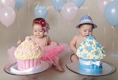 two babies sitting next to each other with cupcakes and balloons in the background